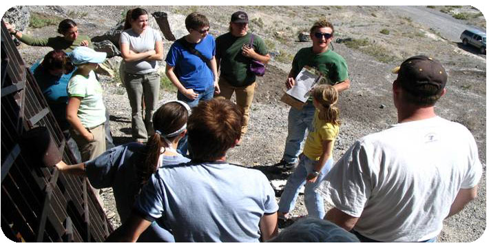 Anthropology students standing in a desert looking at a professor with a clipboard