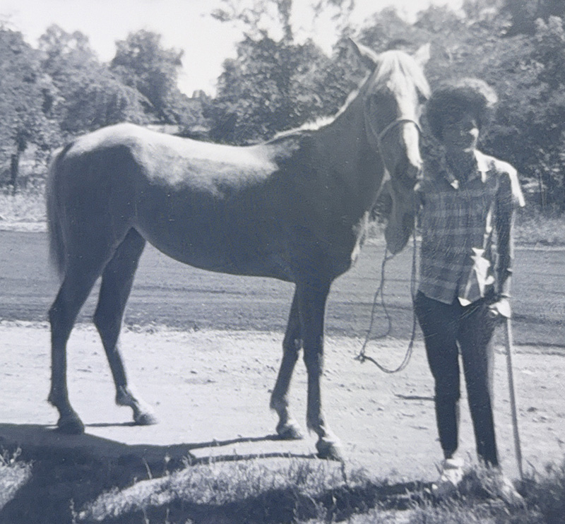 Black and white photo of Julie Chugg Palfreyman standing in front of a horse
