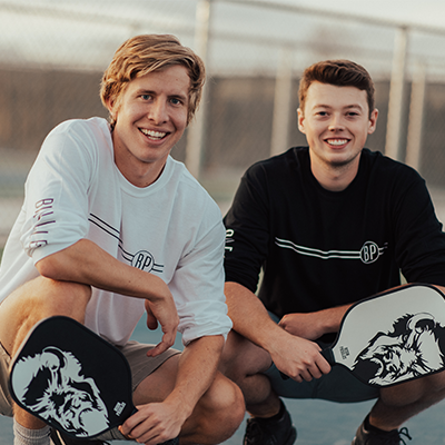 photo of two men in front of a pickleball court
