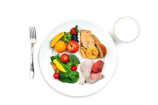 A plate of food seperated by fruit, grain, protein, and vegtables.