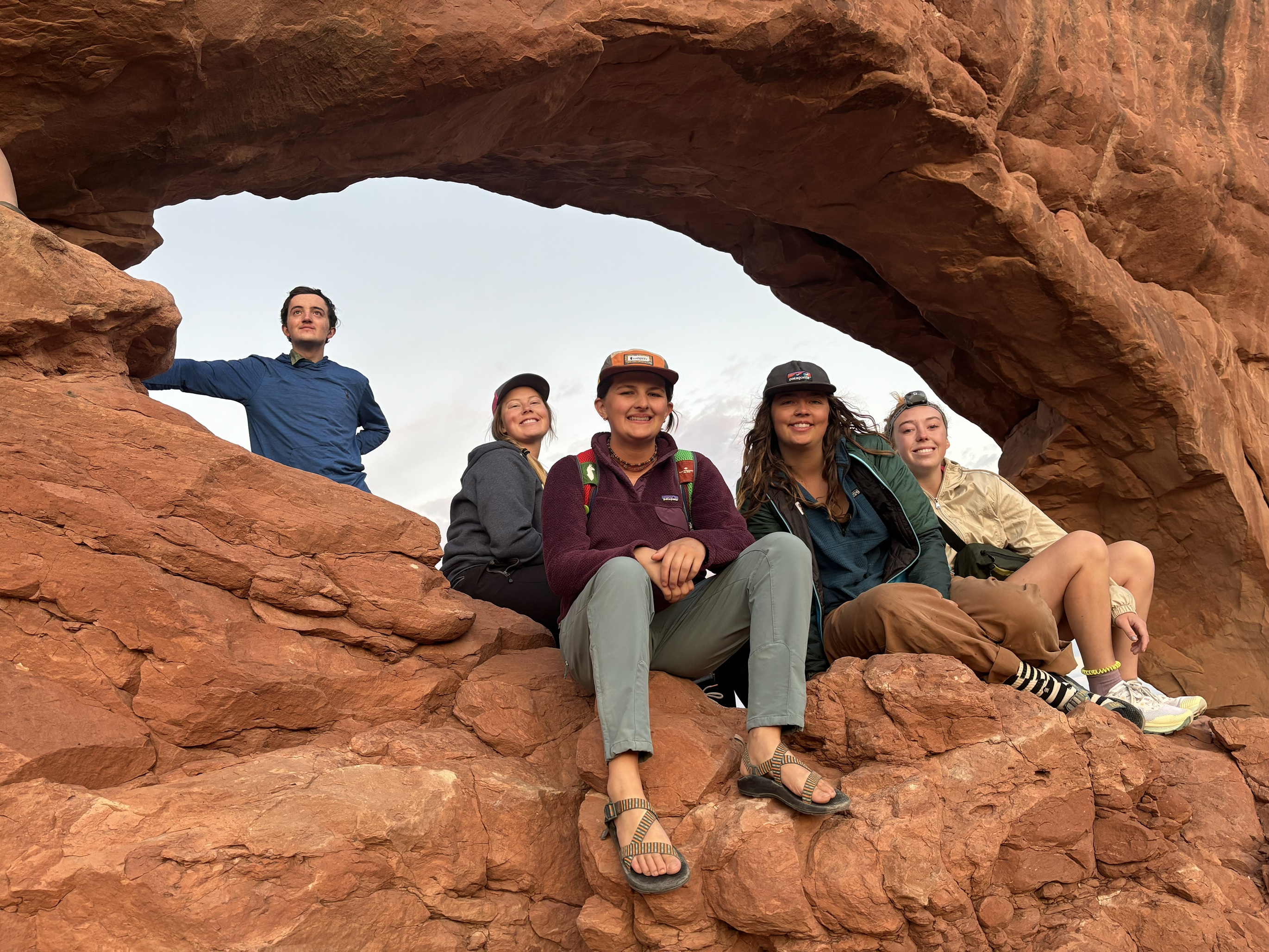 group of people sitting on an Arch in Moab, Utah.