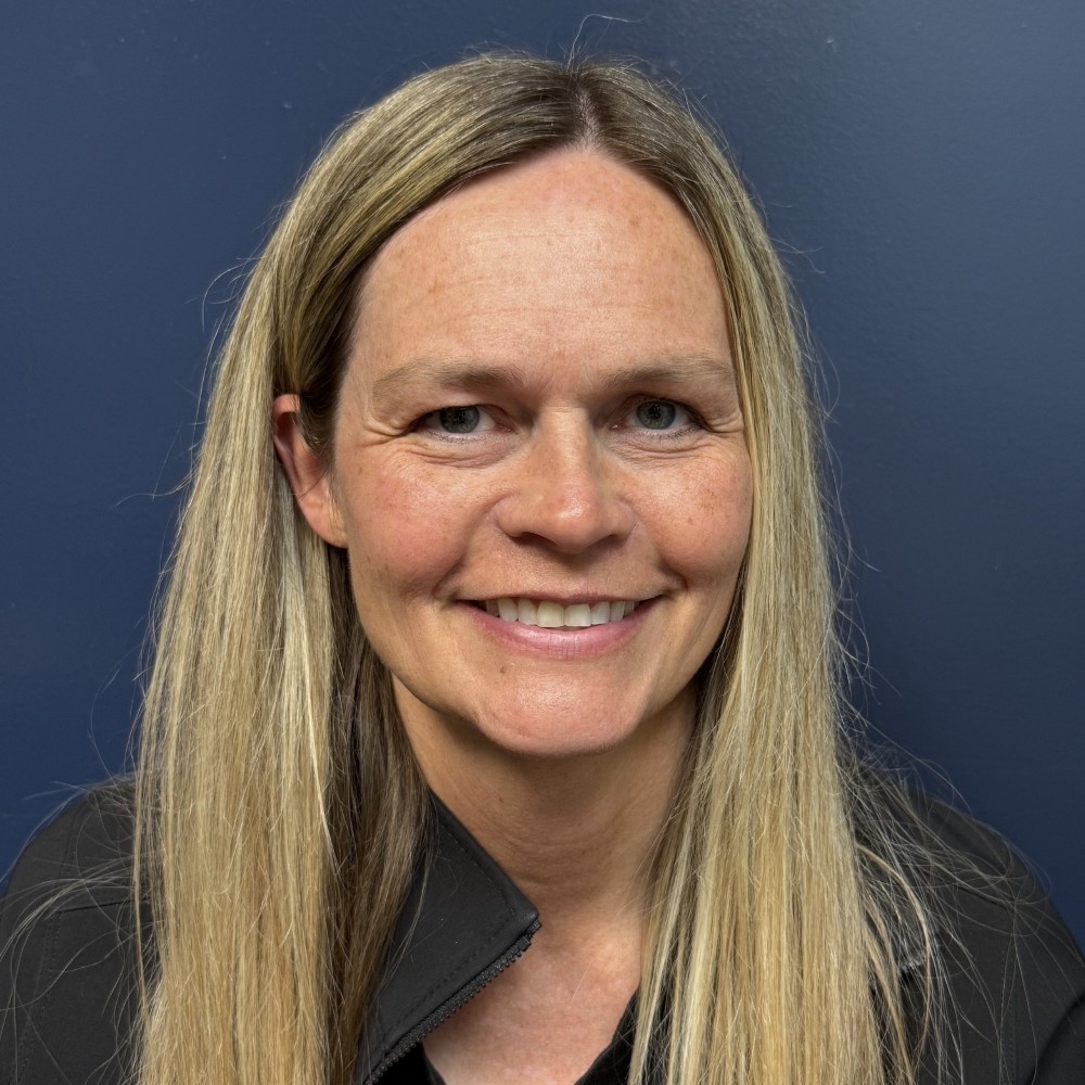 Smiling woman with long blonde hair against a dark blue background