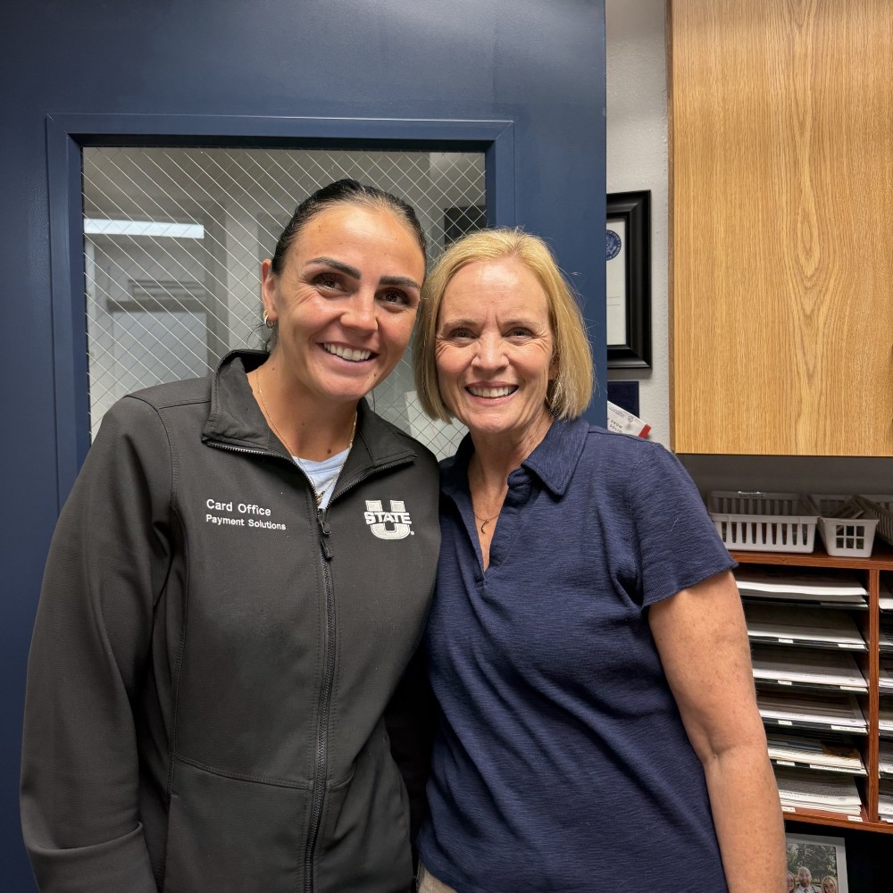 Two smiling women standing together in an office.