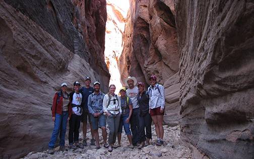 Students stand as the base of a slot canyon