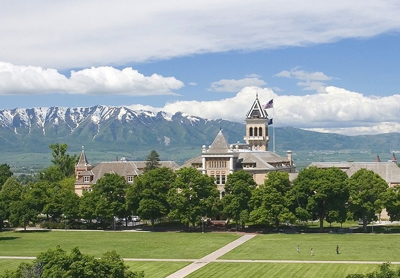 Aerial photo of USU's Old Main with the Quad in the foreground and the Wellsville Mountains in the backgroud