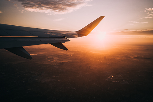Airplane wing with sun in background
