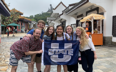 USU Alumnus Megyn Degraw poses with other USU alumni in a Cambodian town