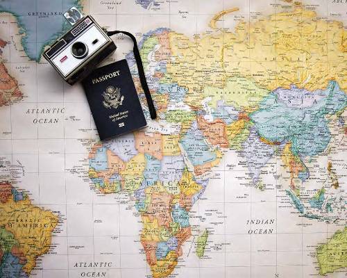 World map with camera and passport lying on top