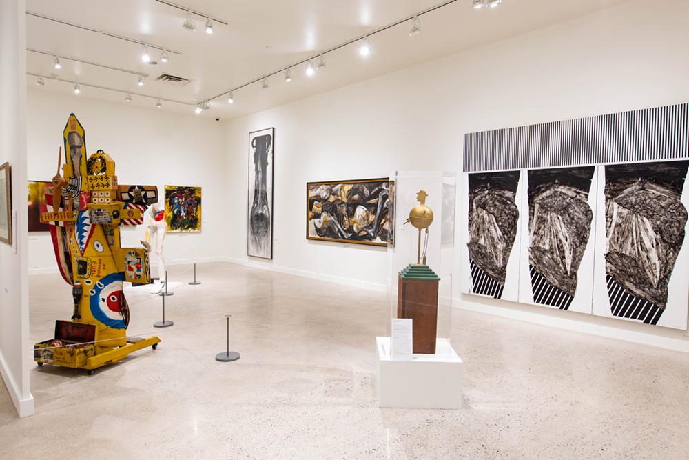 An exhibition room with two main sculpture and large art pieces spanning the walls 