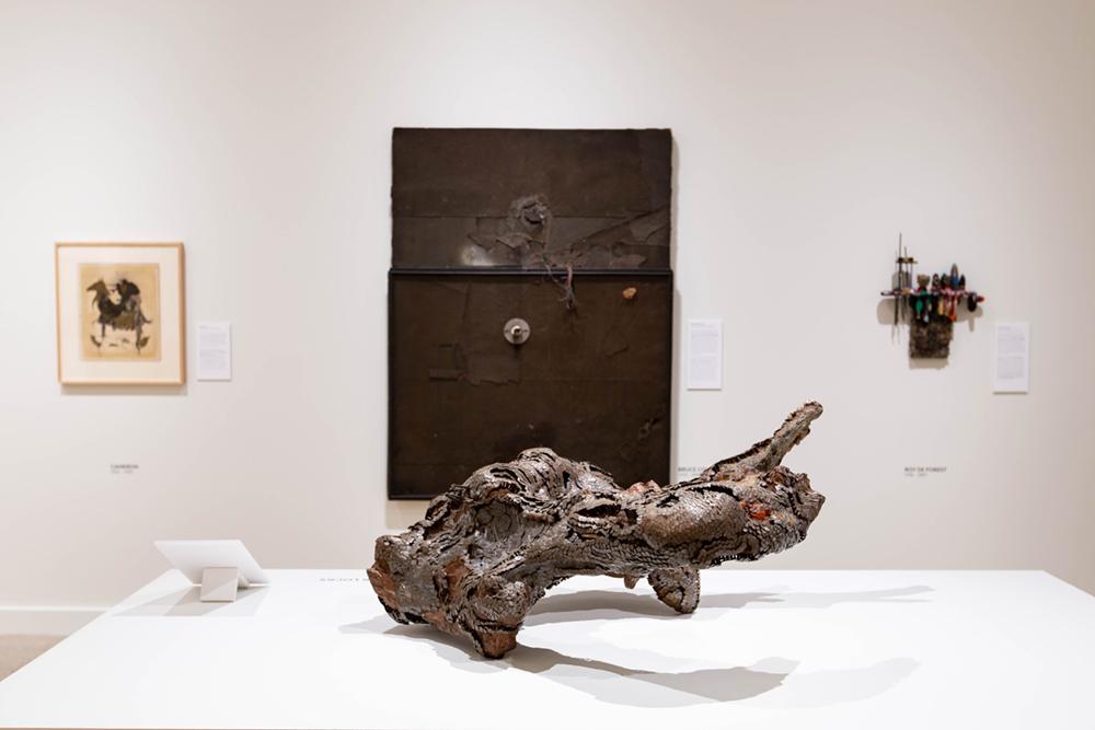 A focal sculpture on the table with three art pieces hung on a wall behind