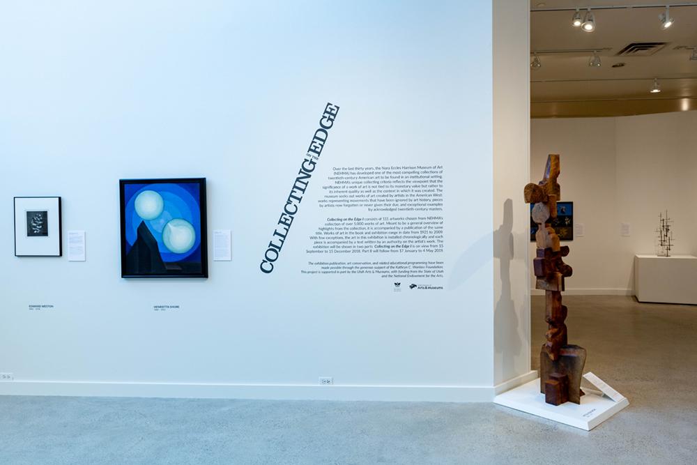 The front of the Collecting Edge exhibit with a vinyl description on the wall and two art pieces