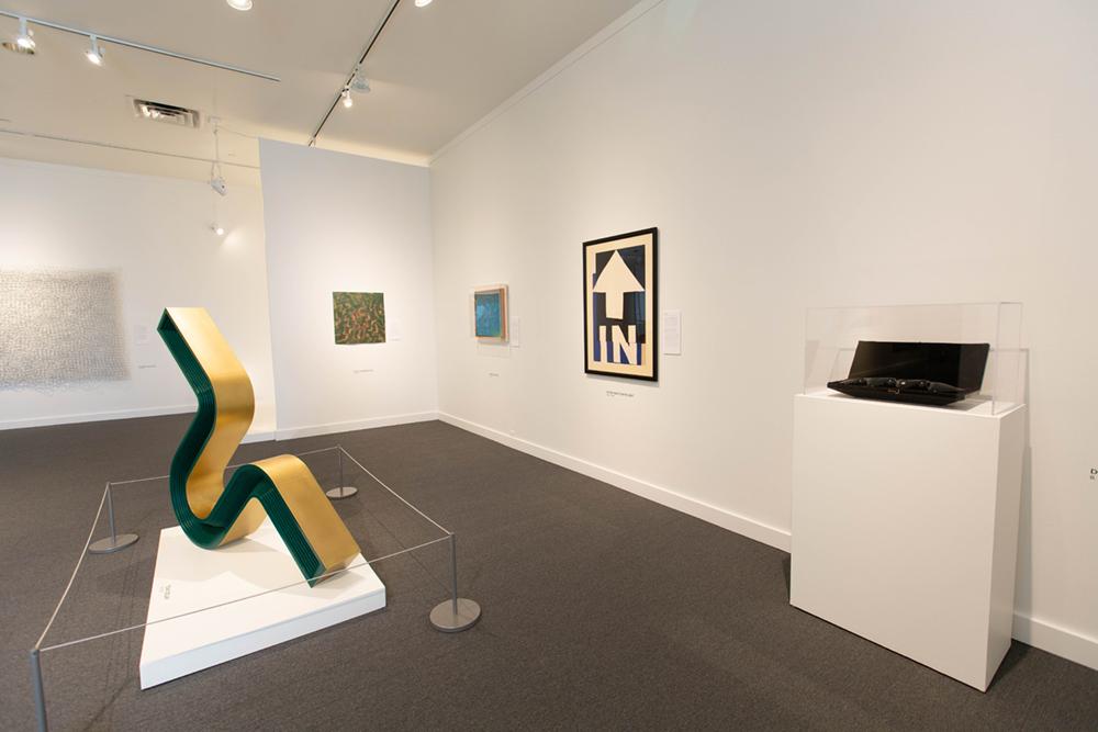 A green and gold sculpture to the left and four art pieces on the right