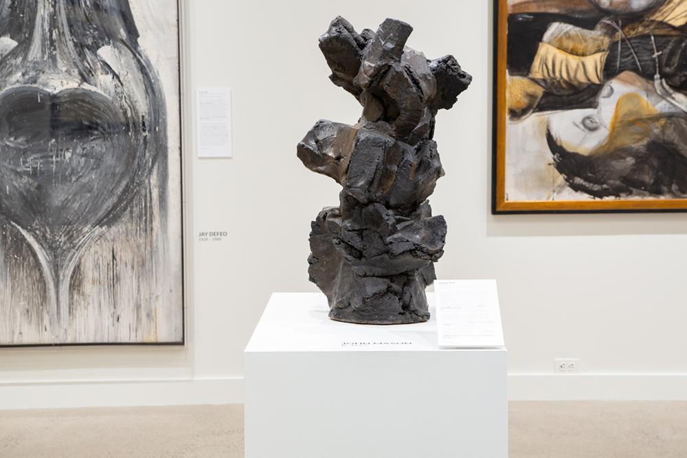 A darkly colored blocky sculpture on a presentation table