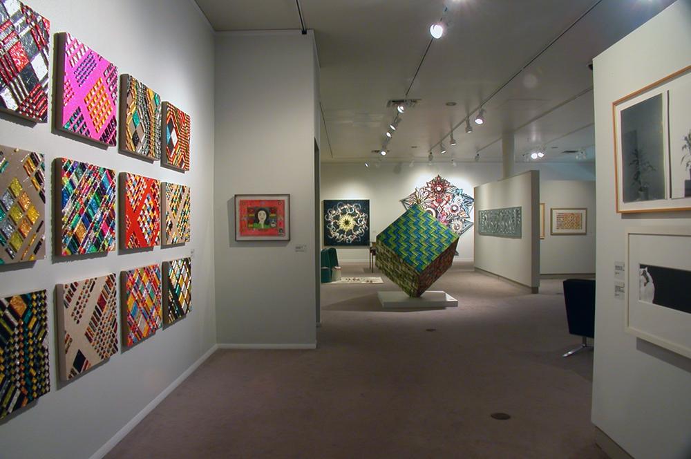 An exhibition space with a large cube sculpture in the middle