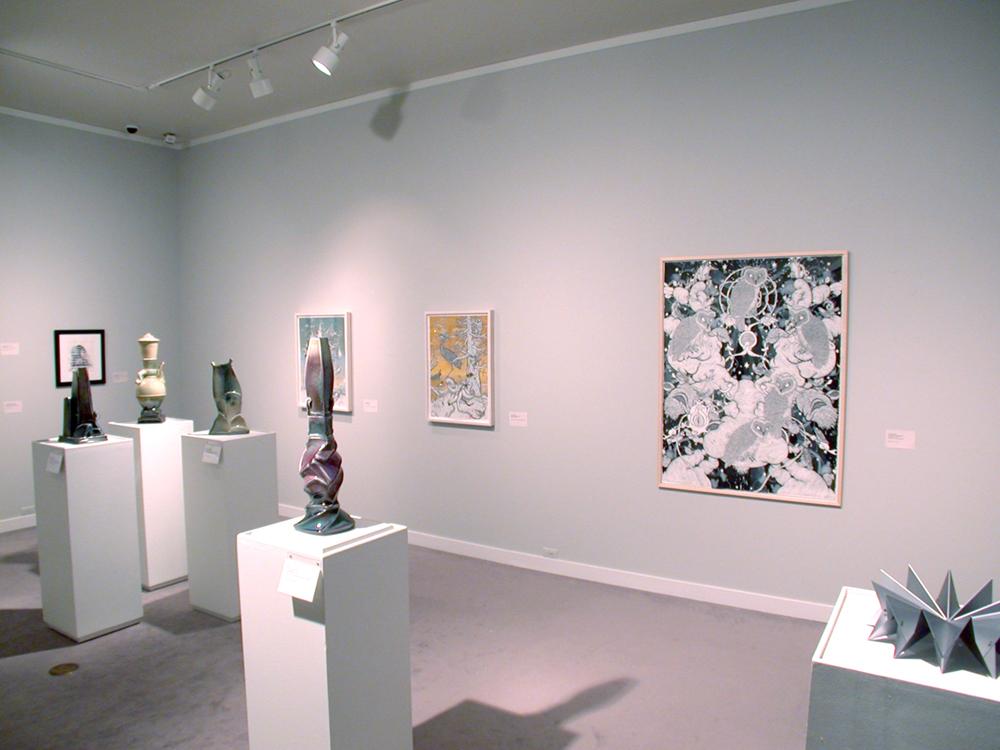 A large framed art piece hangs on the wall with sculptures displayed on tables