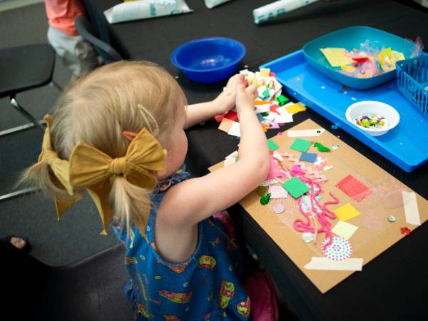 Toddler creating with bits and pieces during Mini Makers class.