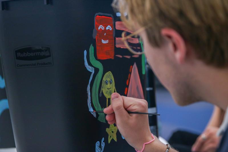 Student painting their recycling bin with different small designs.
