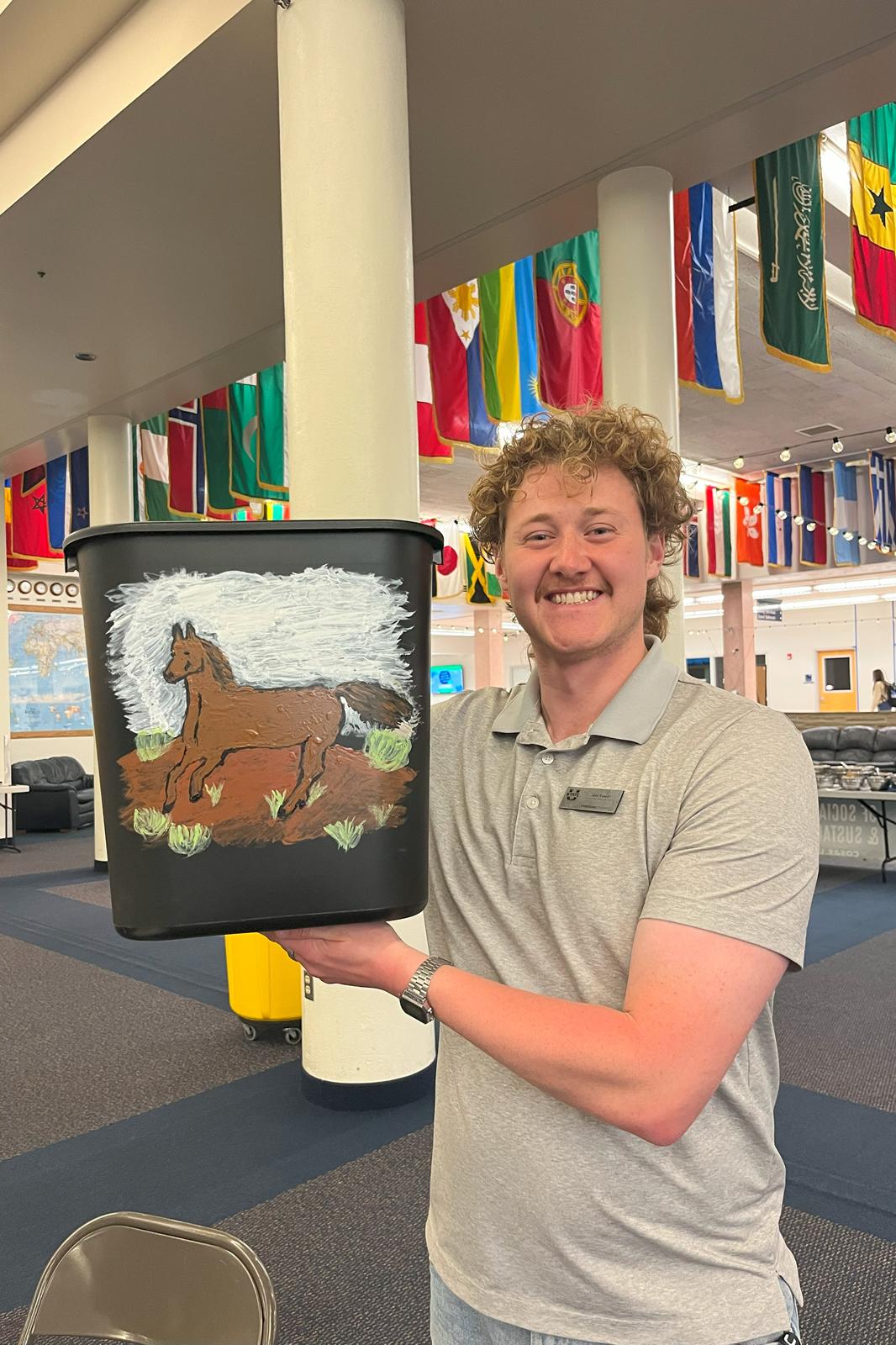 Student holding up their recycling bin with their painting of a horse.