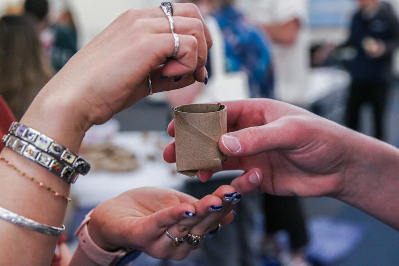 Closeup of hands holding a toilet paper tube pot and planting seeds.