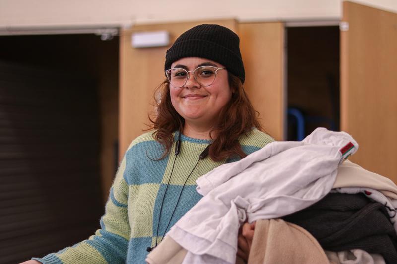 Student smiling while holding clothes.
