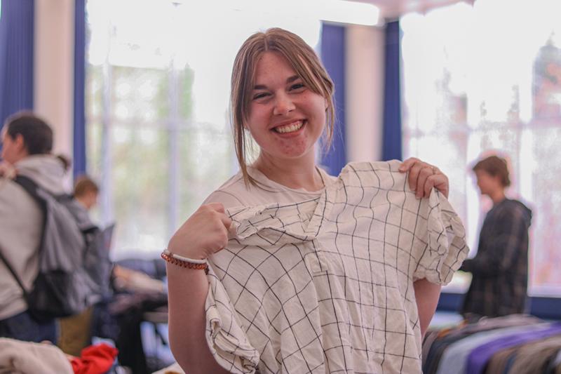 A student holding up a shirt and smiling.