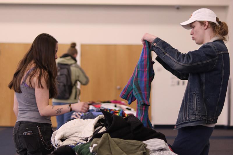 Two students looking through clothes.
