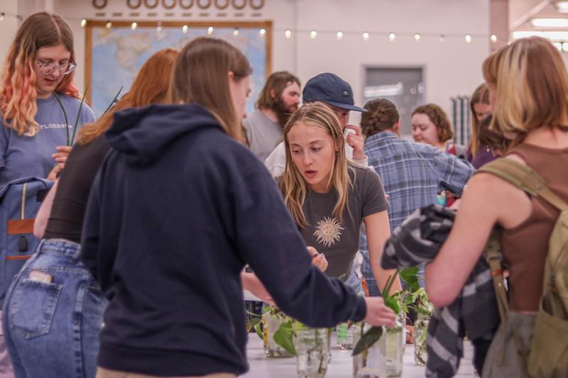 A group of students around a table of plants and reused glass jars.