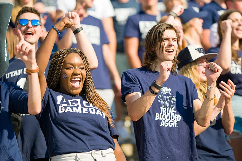 students at a football game with their aggie gear