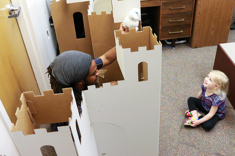 Adult interacting with child in a cardboard castle