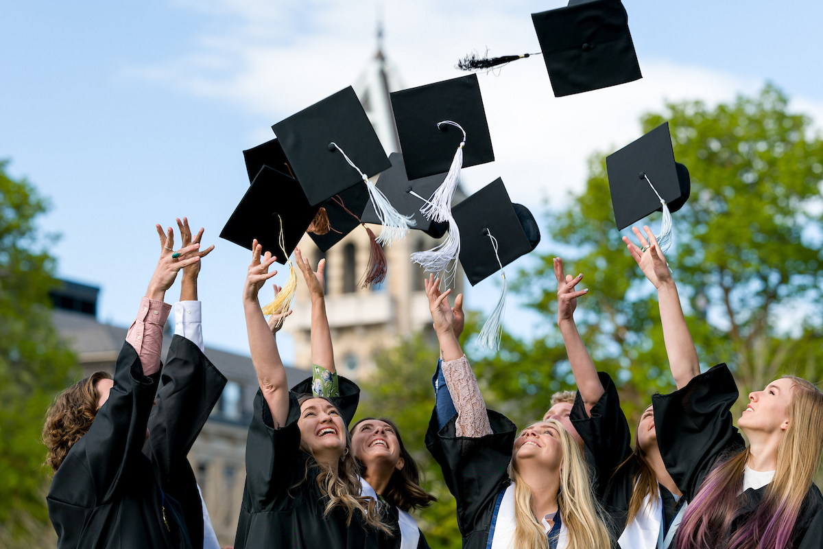 Group of graduates throwing their graduation caps in the air.