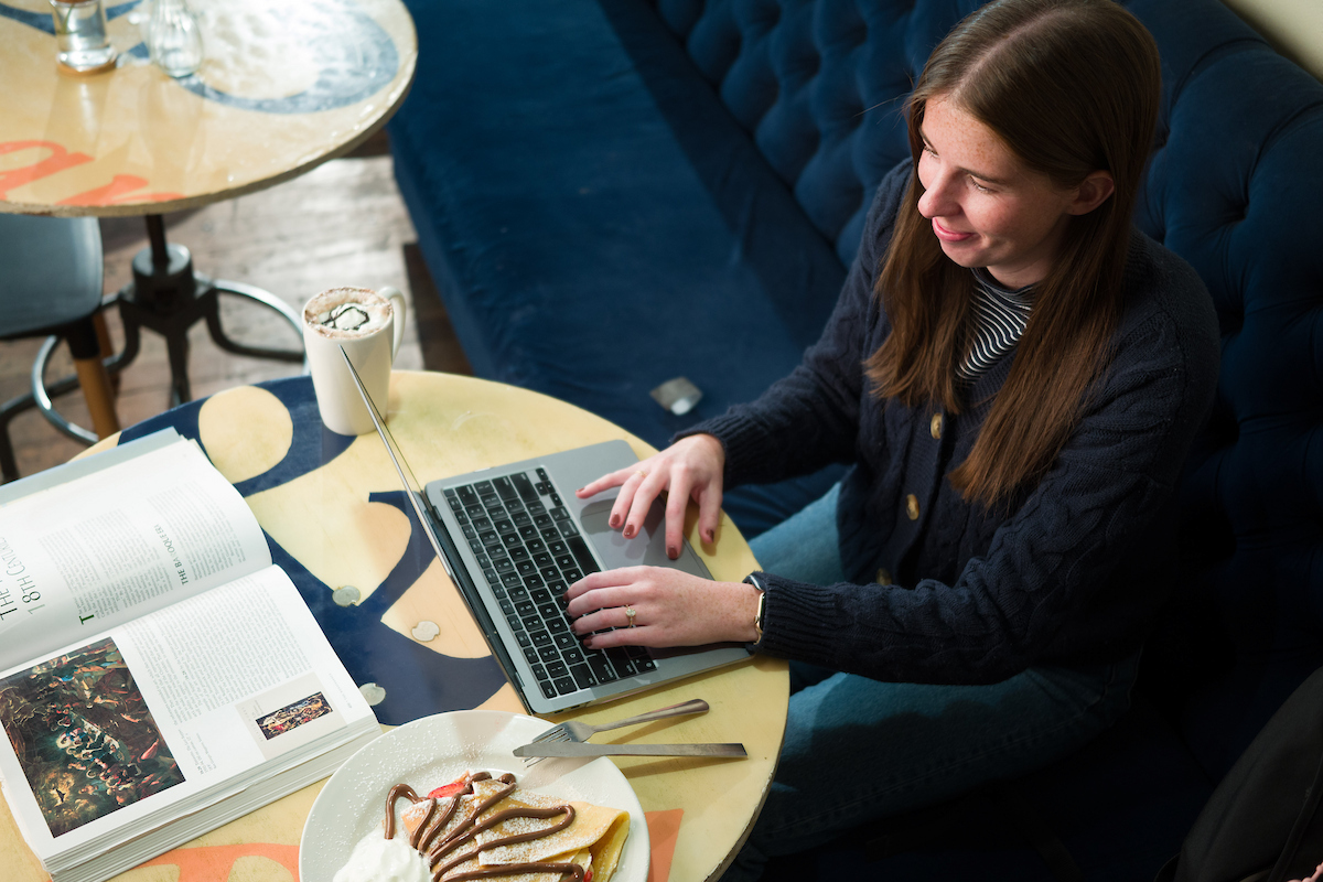 A top down view of a USU Online student sitting at a cafe table while doing coursework.