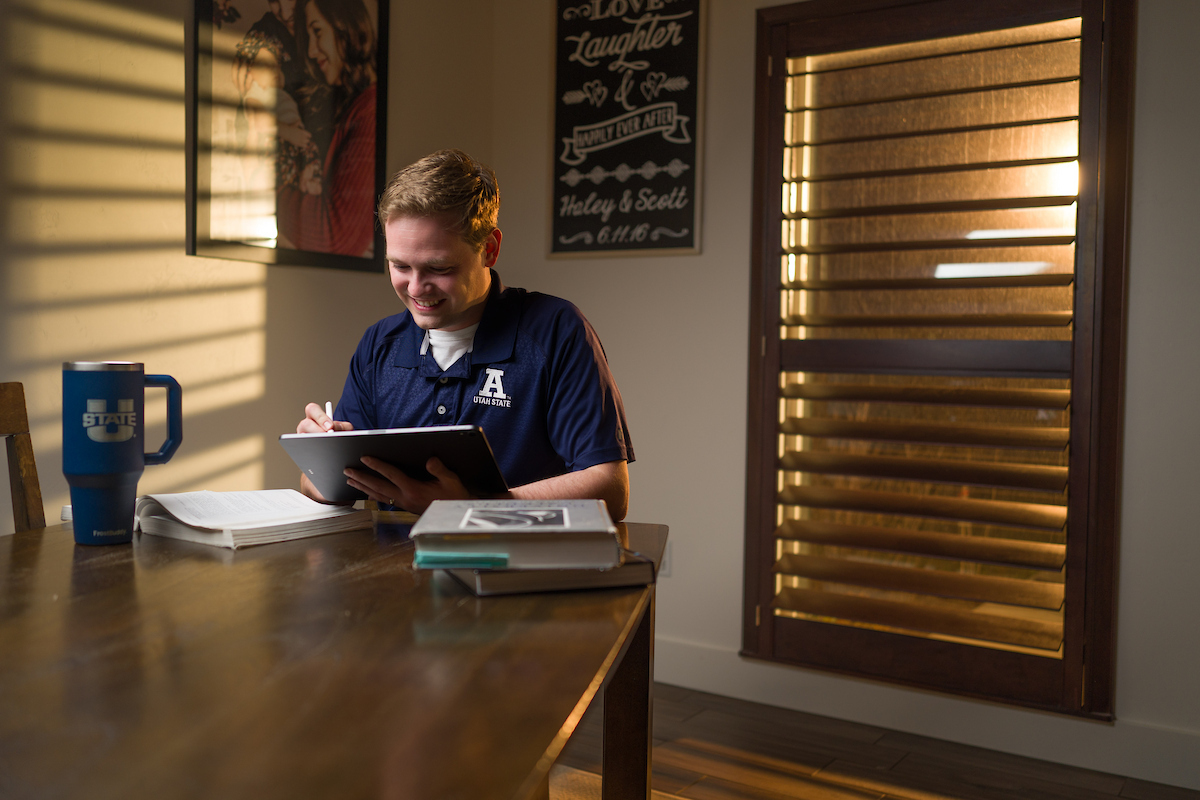 A USU Online students studying at night at his kitchen table.