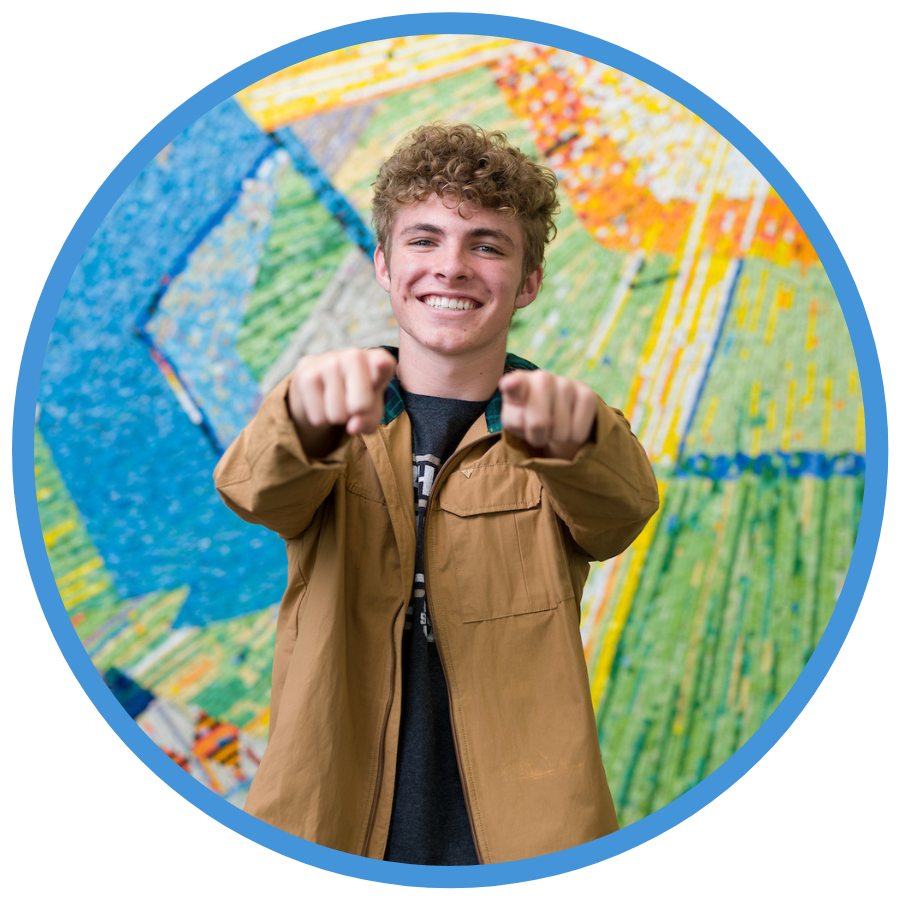 USU student smiling and pointing at the camera.