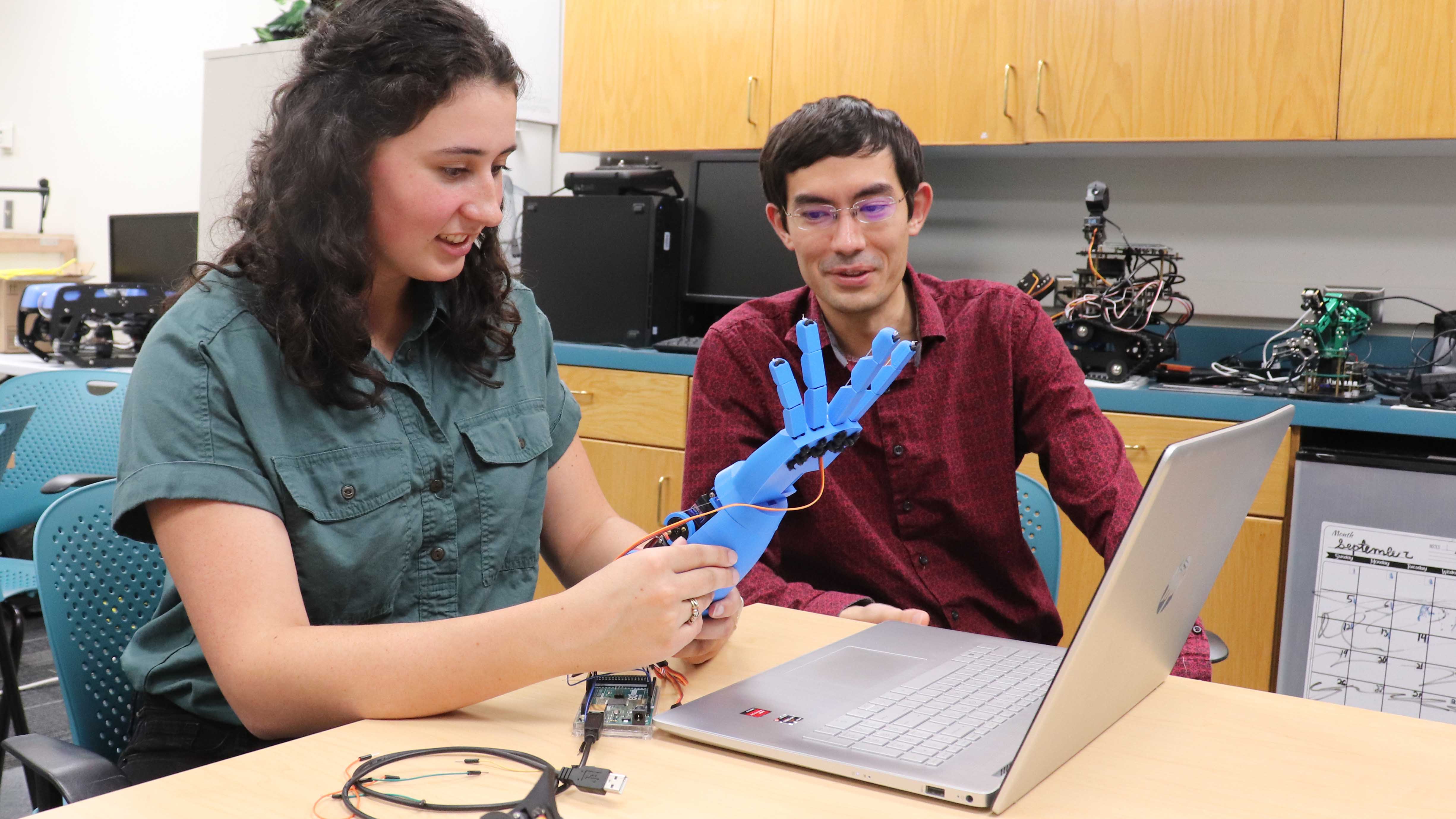 Student and a professor working on a robotic hand. 