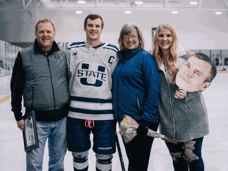Josh Kerkvliet posing in the rink with his family after a USU Hockey match.