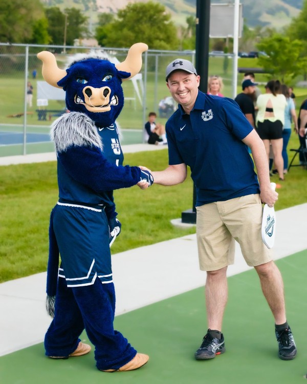 Governor Spencer Cox shakes hands with Big Blue after a pickleball match at USU Brigham City.