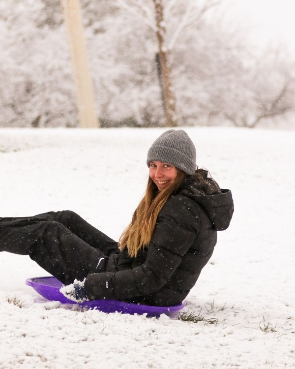 A female USU student sleds down Old Main Hill.