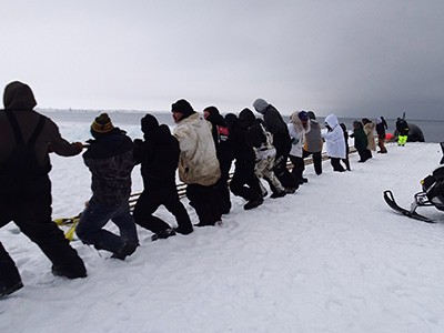 Utqiagvik, Alaska residents haul whale from sea.