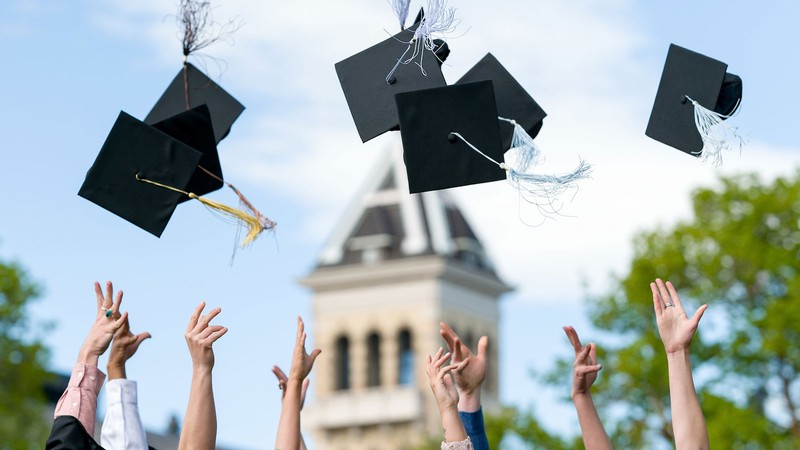 Students throw mortarboards in the air.
