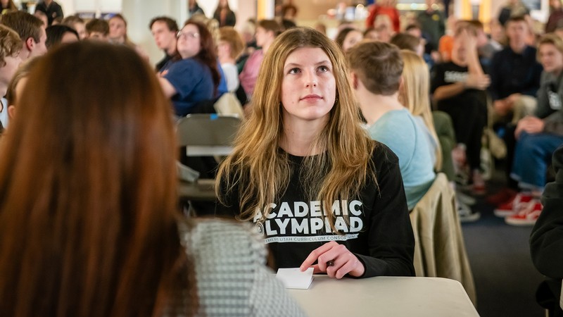 A young woman sits at a table.