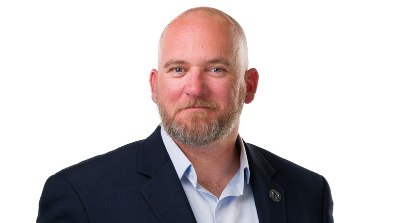 A man poses for a photo with a white background.