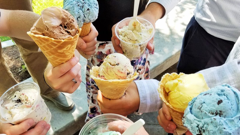 People hold Aggie Ice Cream cones and cups.