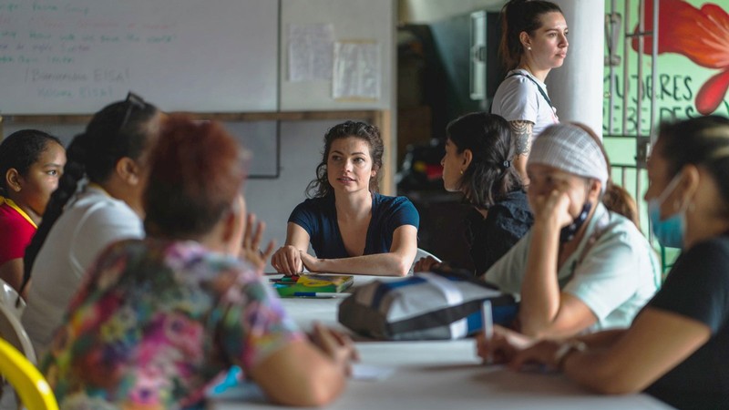 Anna Cheal talks with people seated around a table at the nonprofit Proyecto Florecer in Colombia.