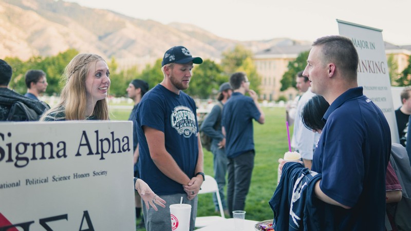 People converse at a Pi Sigma Alpha informational booth on the Quad.