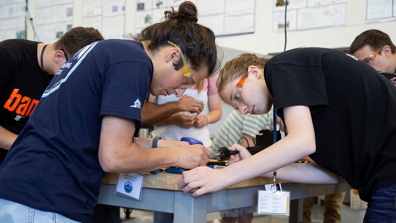 People solder electronics in a laboratory classroom.