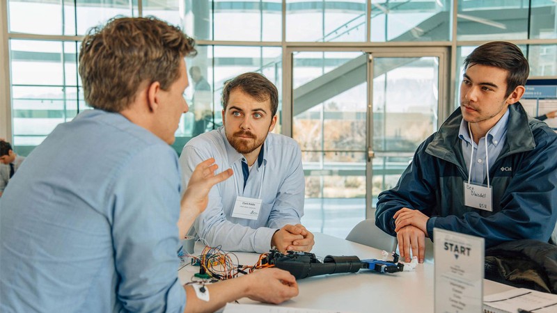 Conference attendees discuss a robotic hand.