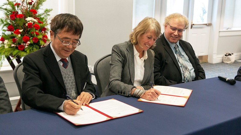 University officials signing documents.