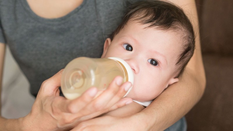 An infant drinks from a bottle.