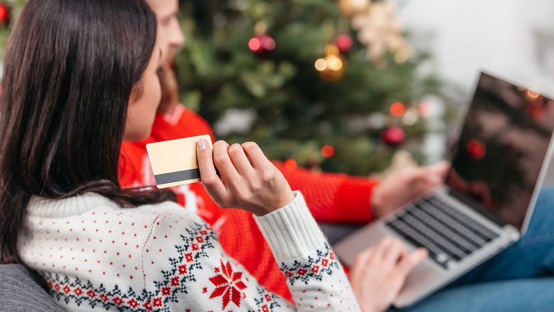 People by a Christmas tree shopping online.