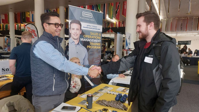 People shake hands at a career fair.